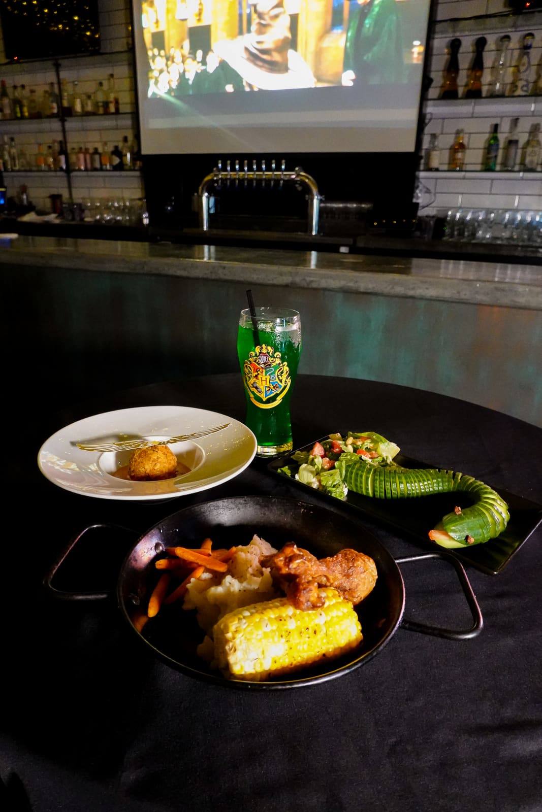 A set table with a green drink and Harry Potter playing on the screen behind