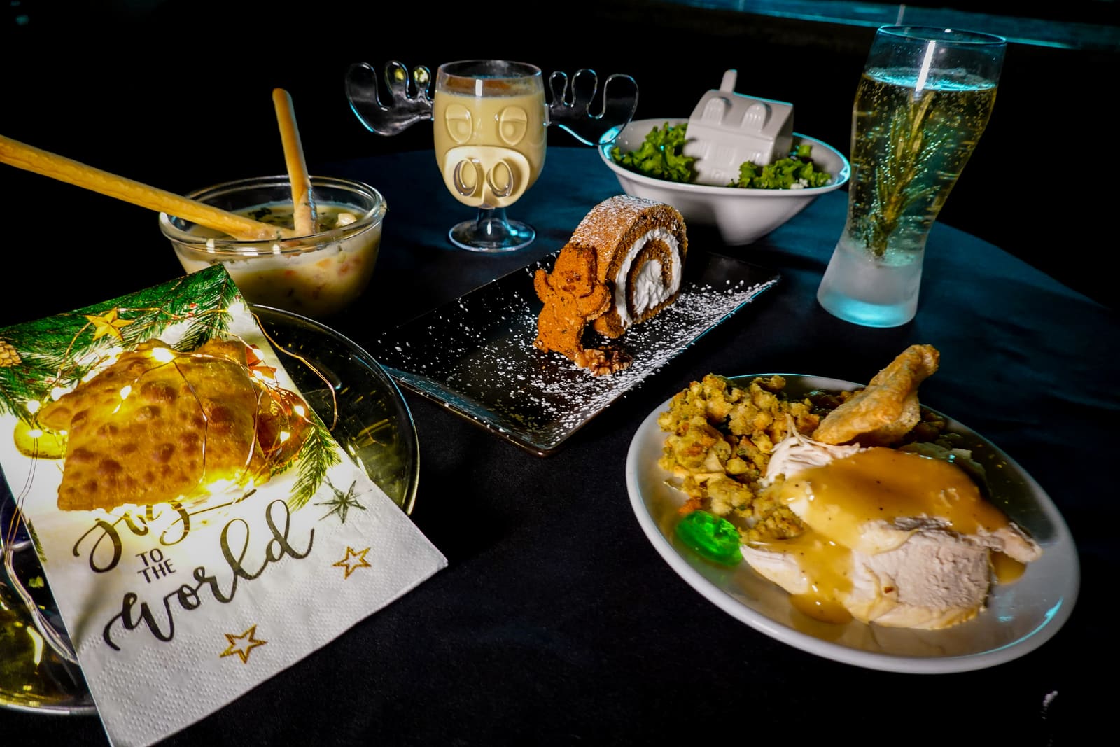A roast turkey course with sides and a sparkling drink next to a printed menu