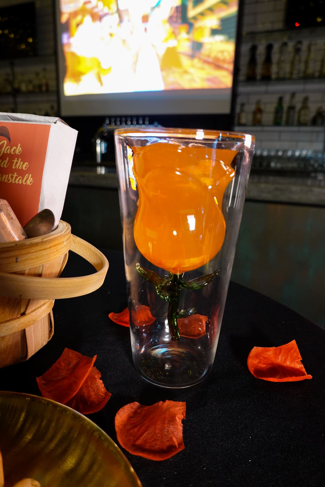 A tall orange cocktail beside a small course in a basket