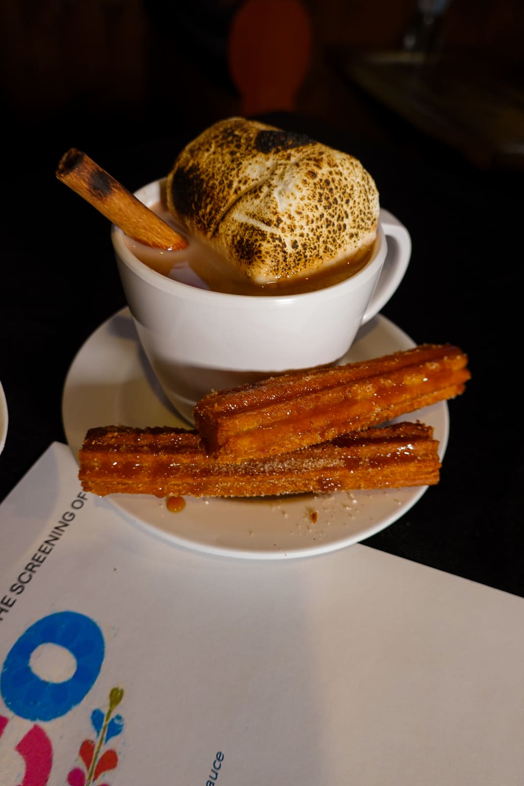 Churros beside a cup of hot chocolate topped with cream