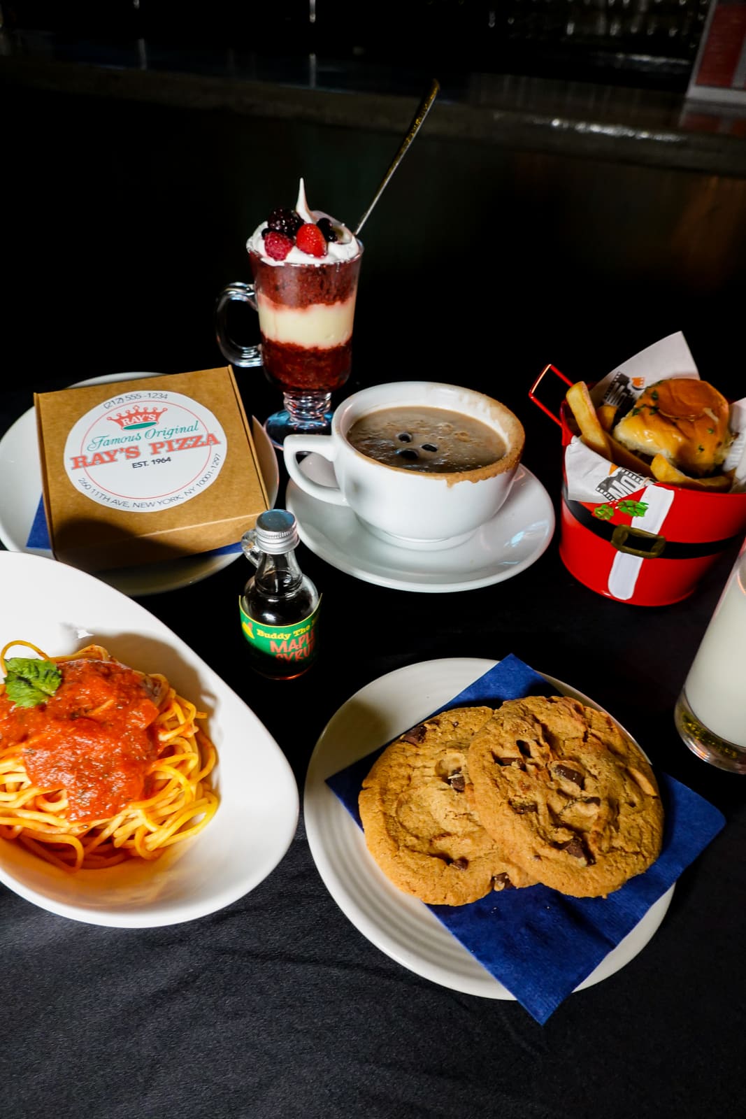 Spaghetti with sauce beside a giant cookie, with a pizza box behind