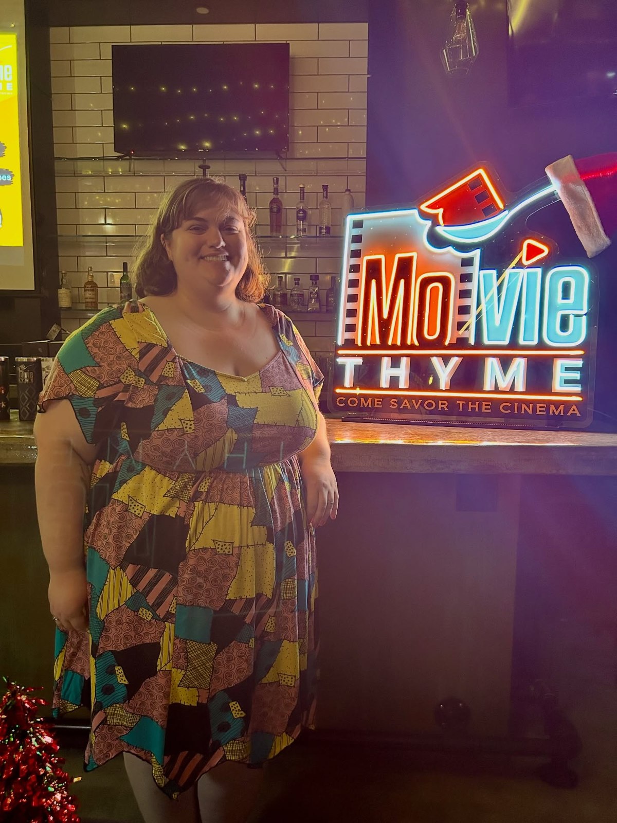 A guest standing beside the Movie Thyme neon sign